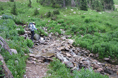 Hiker crossing a creek on rocks