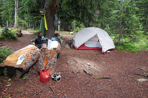 Hiker at campsite with tent and cooking gear